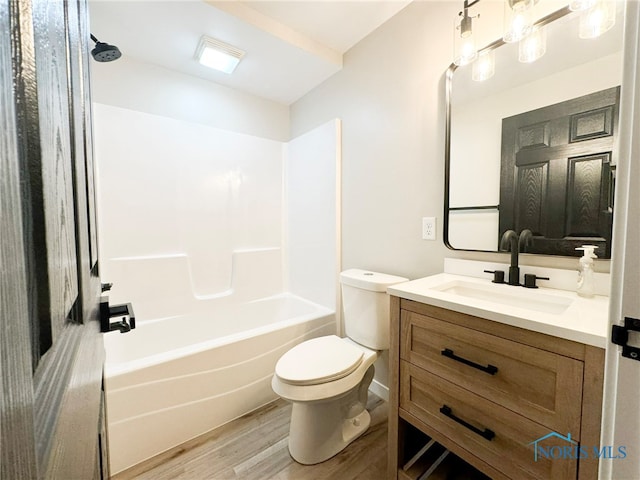 full bathroom with hardwood / wood-style floors, vanity, toilet, and shower / washtub combination