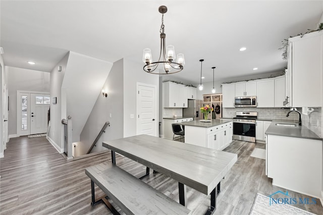 dining area with sink, light hardwood / wood-style flooring, and an inviting chandelier