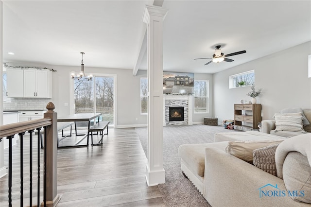 living room featuring ceiling fan with notable chandelier, hardwood / wood-style flooring, a fireplace, and a wealth of natural light