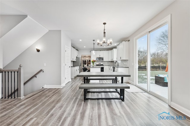 dining room with light wood-type flooring, a notable chandelier, and sink