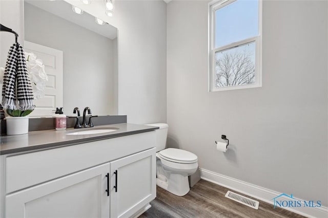 bathroom with toilet, vanity, and hardwood / wood-style floors