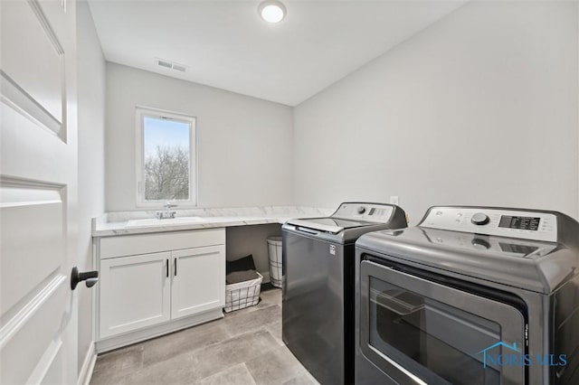 laundry area featuring cabinets, washer and clothes dryer, and sink