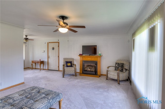 sitting room with carpet, ceiling fan, and ornamental molding