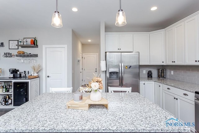 kitchen with stainless steel refrigerator with ice dispenser, tasteful backsplash, pendant lighting, white cabinets, and a center island