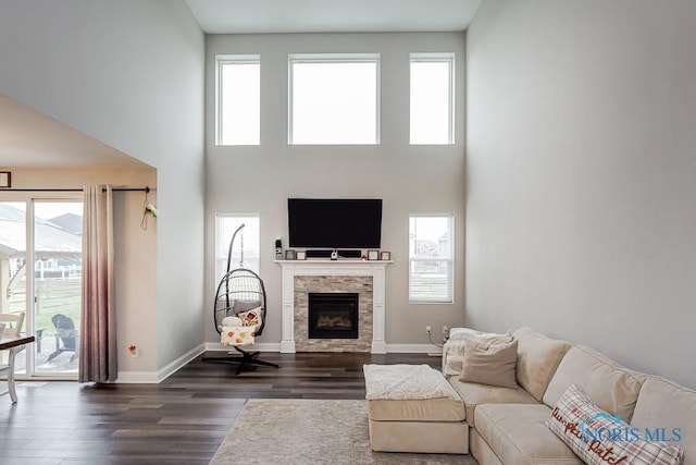 living room featuring a fireplace, a towering ceiling, and dark hardwood / wood-style floors