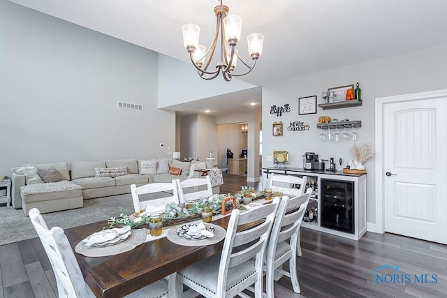 dining space with indoor bar, dark hardwood / wood-style flooring, an inviting chandelier, and beverage cooler