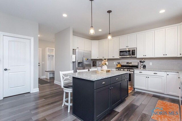 kitchen with white cabinets, a center island, appliances with stainless steel finishes, and pendant lighting