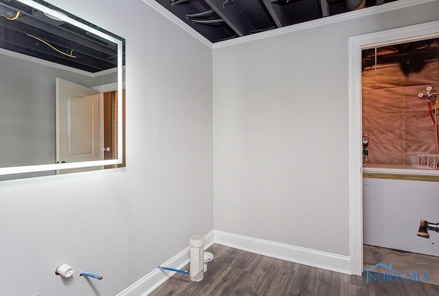 clothes washing area featuring crown molding and dark wood-type flooring