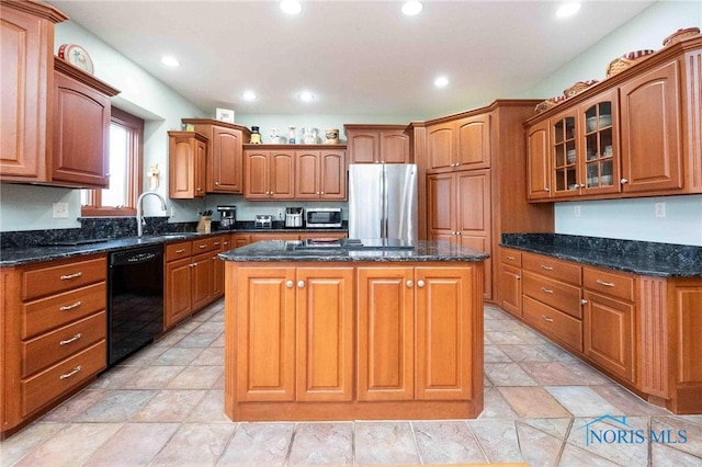 kitchen with a center island, stainless steel appliances, dark stone counters, and sink