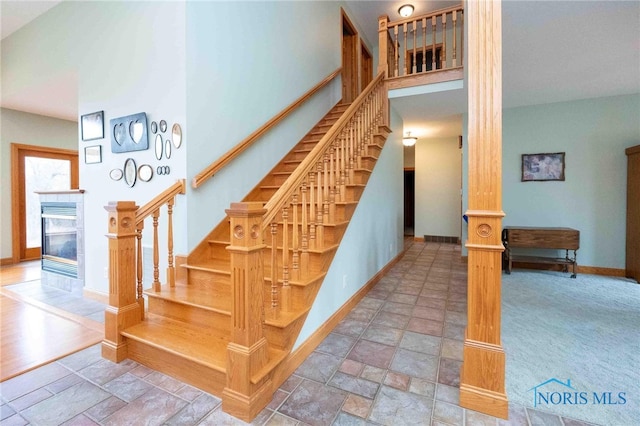 staircase featuring a tile fireplace and a high ceiling