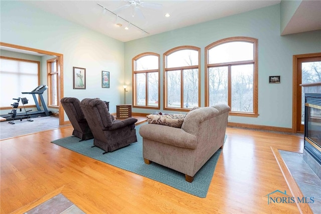 living room with ceiling fan, a tiled fireplace, and light hardwood / wood-style flooring