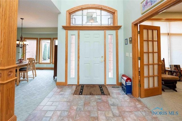 carpeted entryway with a chandelier