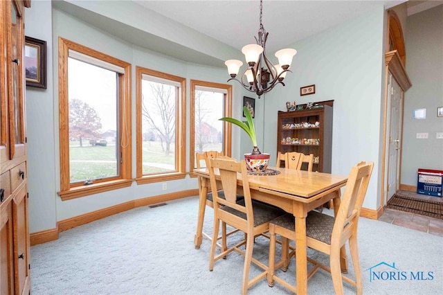 carpeted dining area featuring a chandelier