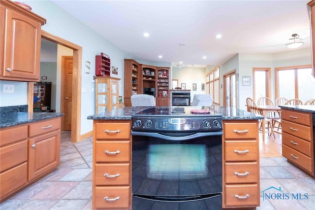 kitchen with a center island, black range with electric stovetop, and dark stone counters