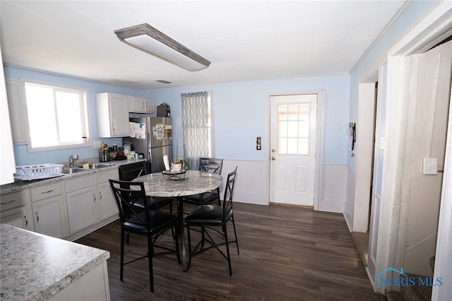 dining space with sink, ornamental molding, and dark wood-type flooring