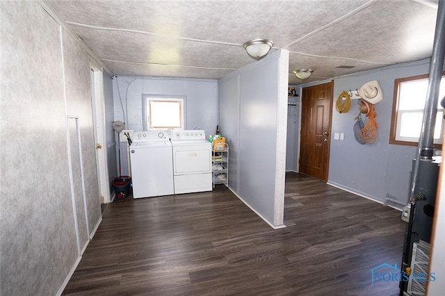 clothes washing area featuring dark wood-type flooring, a wealth of natural light, and washing machine and clothes dryer