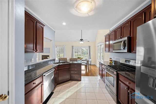 kitchen featuring appliances with stainless steel finishes, dark stone counters, vaulted ceiling, ceiling fan, and light tile patterned floors