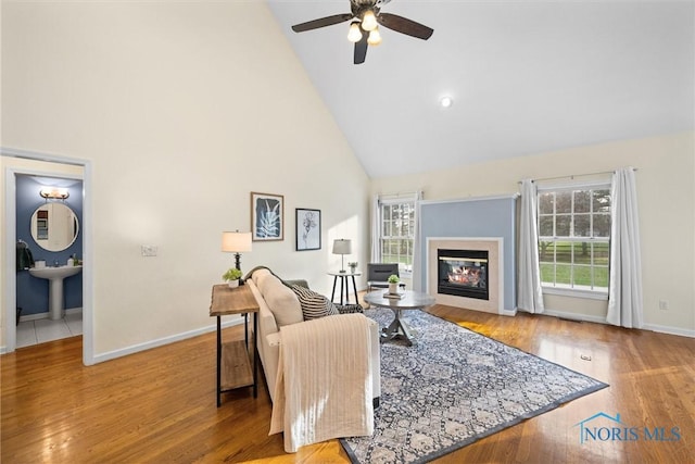 living room with hardwood / wood-style floors, high vaulted ceiling, ceiling fan, and sink