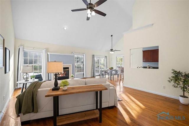 living room featuring hardwood / wood-style floors, high vaulted ceiling, and ceiling fan