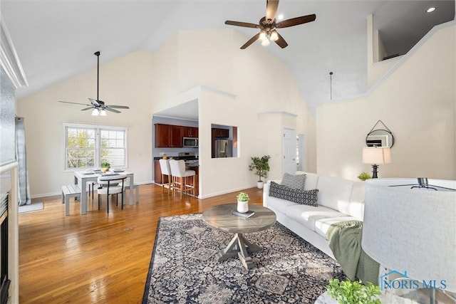 living room with ceiling fan, high vaulted ceiling, and hardwood / wood-style flooring