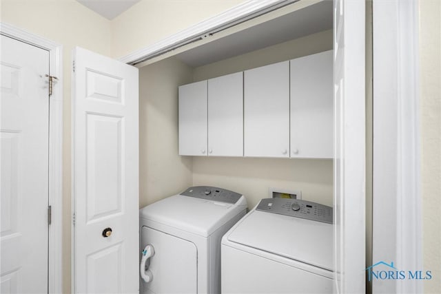 clothes washing area featuring cabinets and separate washer and dryer