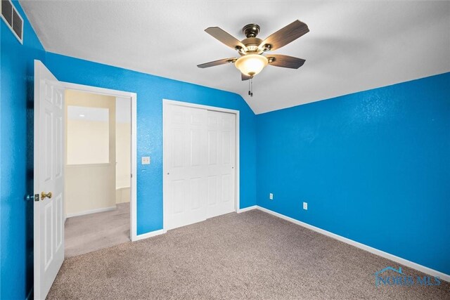 unfurnished bedroom featuring ceiling fan, lofted ceiling, carpet floors, and a closet