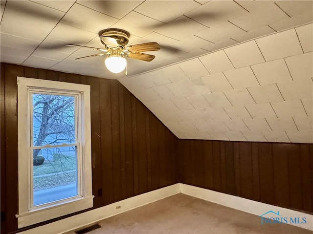 bonus room featuring ceiling fan, wooden walls, and vaulted ceiling