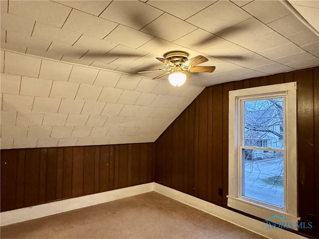 bonus room with vaulted ceiling, ceiling fan, and wooden walls