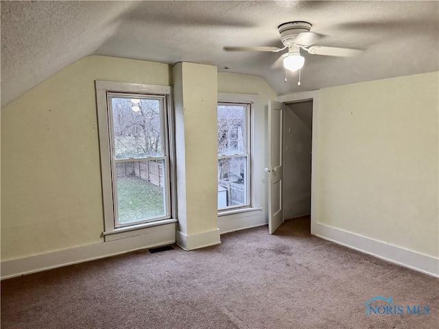 additional living space featuring a textured ceiling, ceiling fan, light colored carpet, and lofted ceiling