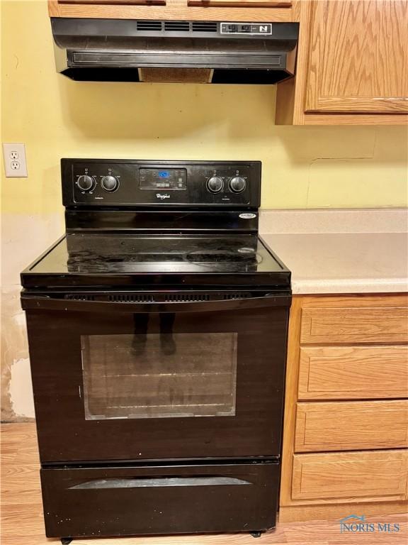 kitchen featuring black range with electric stovetop, light hardwood / wood-style floors, and ventilation hood