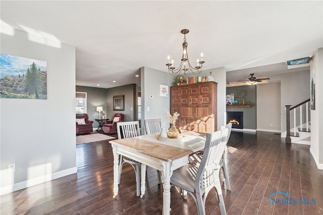 dining space with ceiling fan with notable chandelier and dark hardwood / wood-style floors