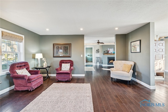 living room featuring a textured ceiling, dark hardwood / wood-style flooring, and ceiling fan