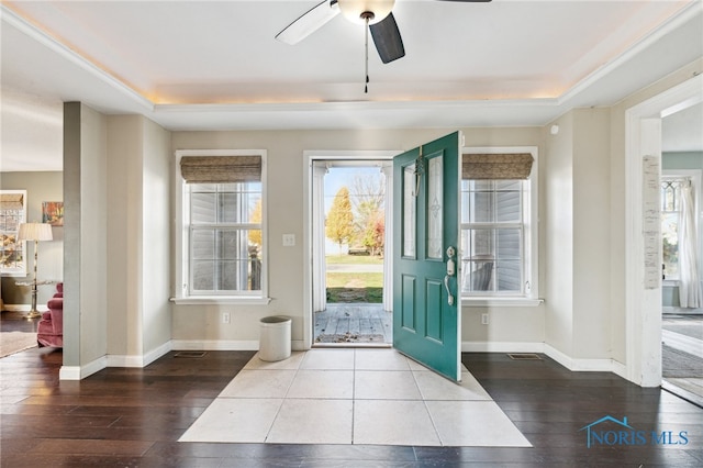 foyer entrance with hardwood / wood-style floors, ceiling fan, and a raised ceiling