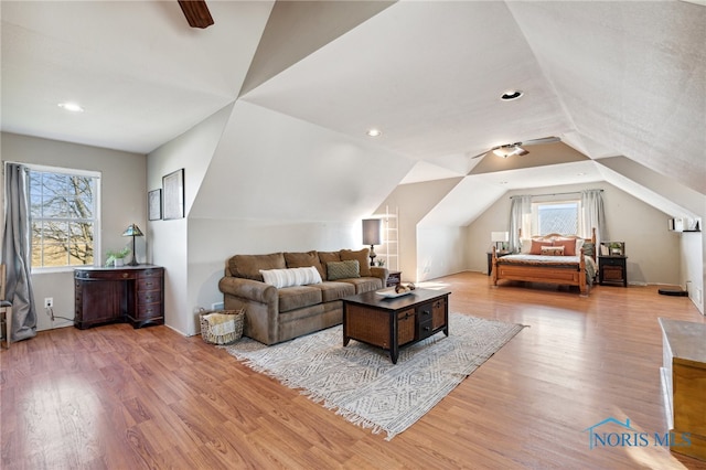 living room featuring light wood-type flooring, vaulted ceiling, and plenty of natural light