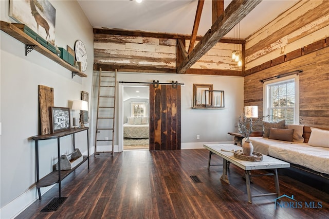 living room with a barn door, wooden walls, a high ceiling, and hardwood / wood-style flooring