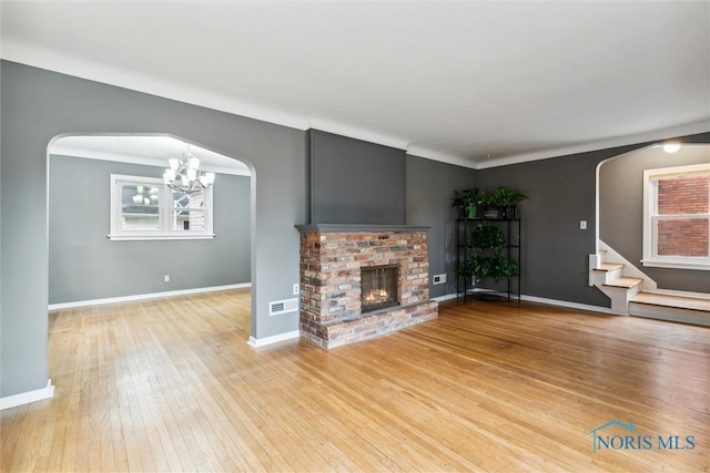 unfurnished living room featuring a fireplace, a notable chandelier, and hardwood / wood-style flooring