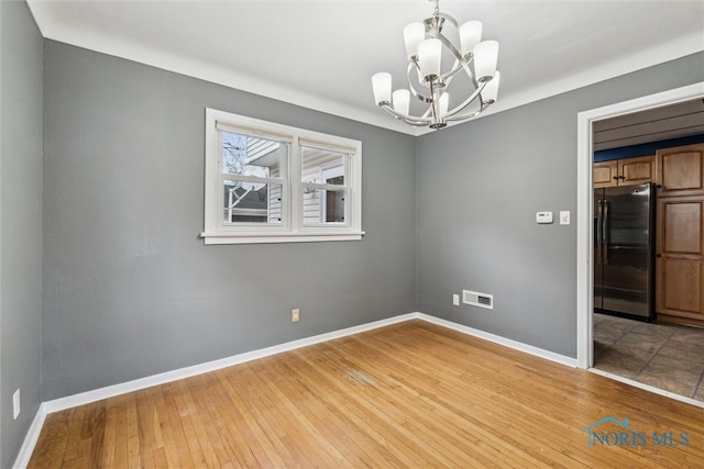 unfurnished room with light hardwood / wood-style floors and a chandelier