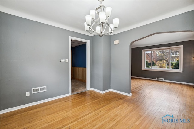 spare room with hardwood / wood-style floors and a notable chandelier