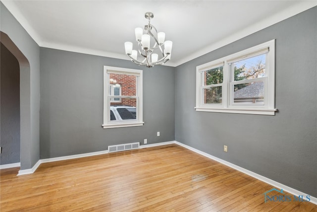 spare room featuring a chandelier and light hardwood / wood-style floors