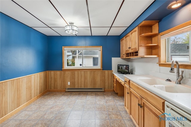 kitchen with a baseboard heating unit, white dishwasher, sink, wooden walls, and light tile patterned floors