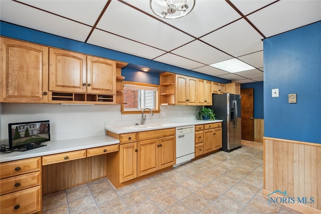 kitchen with a paneled ceiling, dishwasher, sink, wooden walls, and stainless steel fridge with ice dispenser