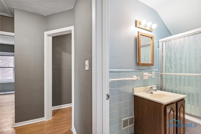 bathroom featuring walk in shower, hardwood / wood-style floors, lofted ceiling, vanity, and tile walls