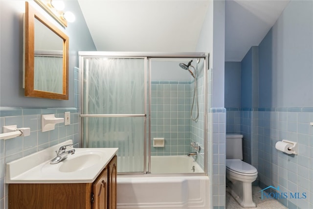 full bathroom with tile patterned flooring, toilet, vanity, tile walls, and tiled shower / bath