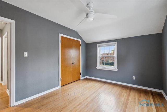 unfurnished bedroom with a closet, ceiling fan, light hardwood / wood-style flooring, and vaulted ceiling