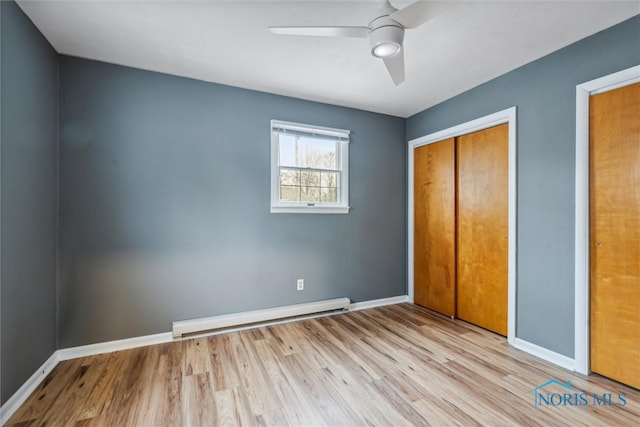 unfurnished bedroom featuring ceiling fan, light wood-type flooring, baseboard heating, and a closet