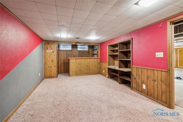 basement featuring wood walls and light carpet