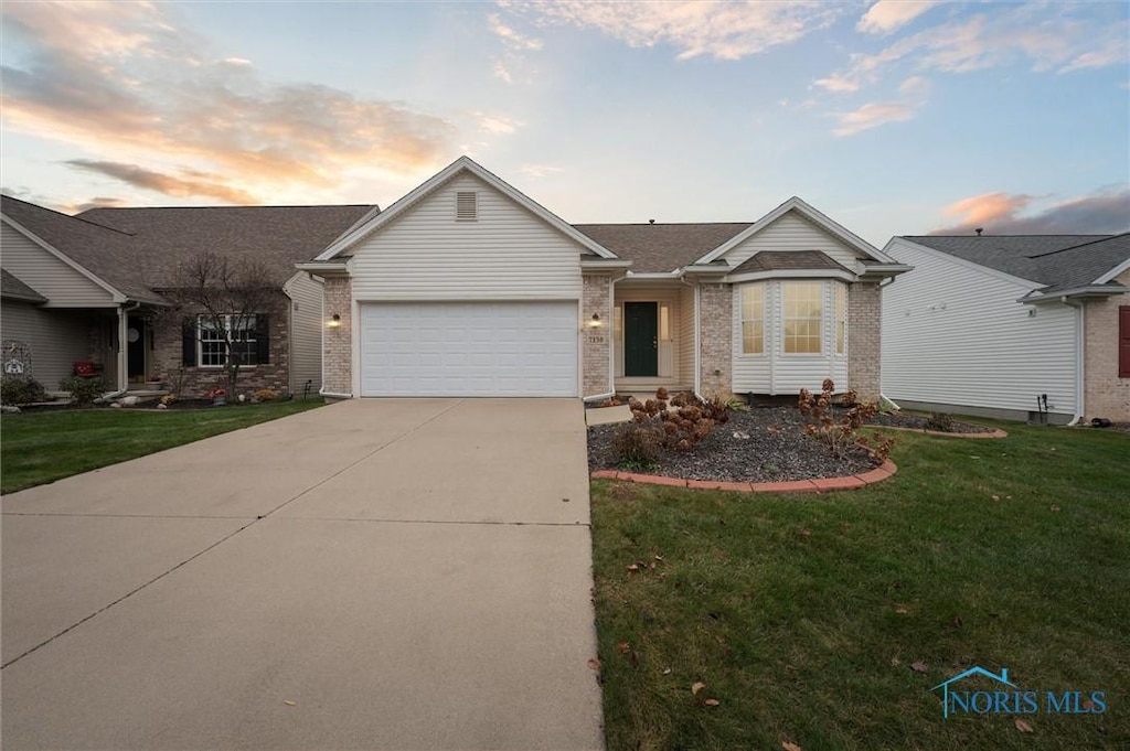 ranch-style house featuring a garage and a yard