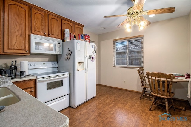 kitchen featuring hardwood / wood-style floors, ceiling fan, white appliances, and sink