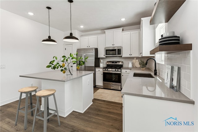 kitchen featuring dark hardwood / wood-style flooring, stainless steel appliances, sink, a center island, and white cabinetry