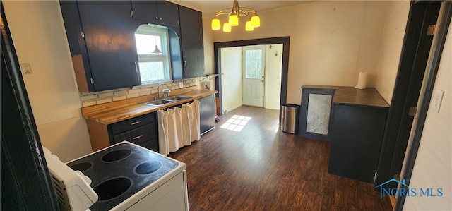 kitchen featuring stove, backsplash, sink, hanging light fixtures, and dark hardwood / wood-style flooring